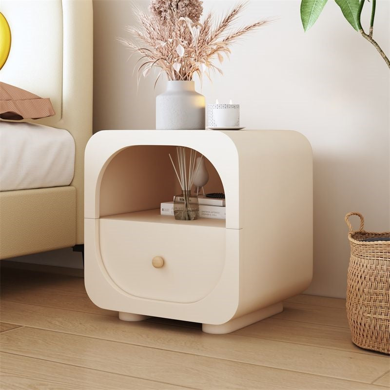 Cream nightstand with glass drawer detail beside a modern bed