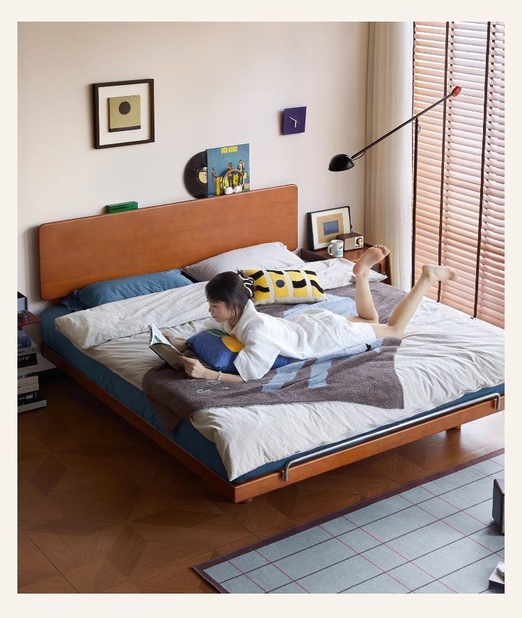 Solid wood platform bed in a bright bedroom with simple layered linens