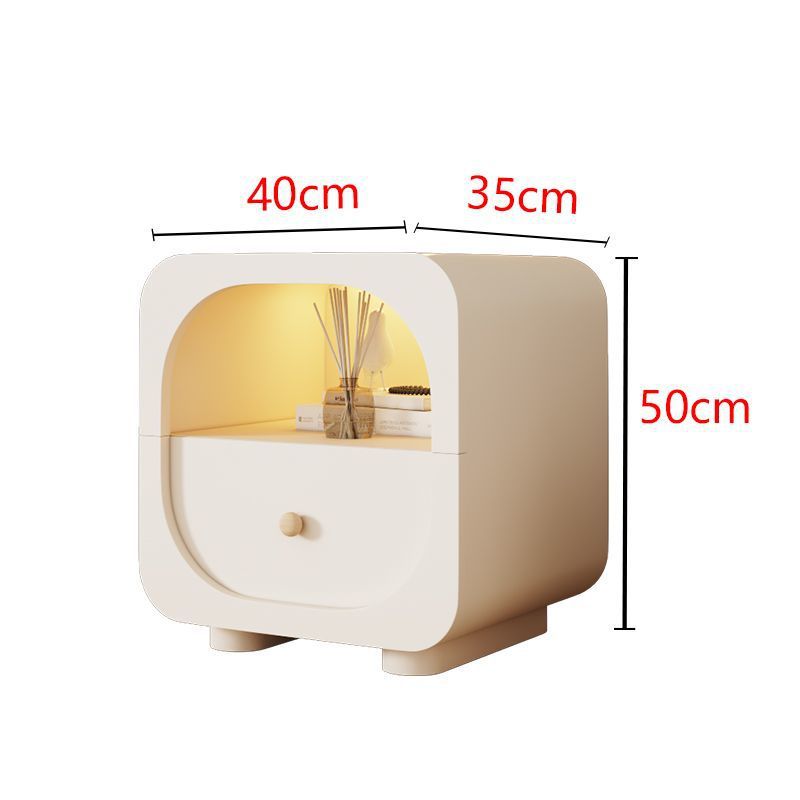 Compact cream nightstand styled beside a neutral upholstered bed