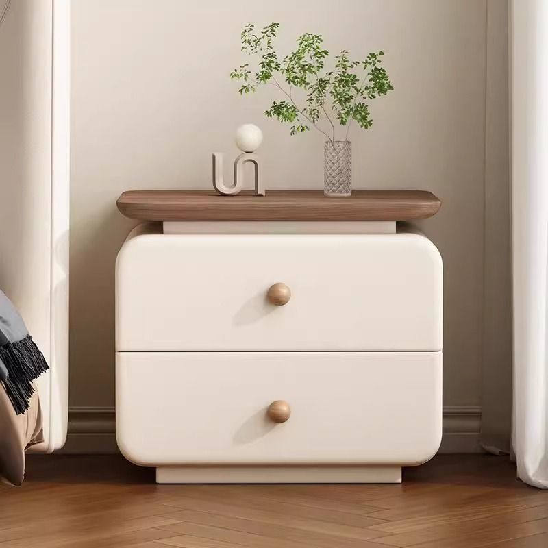 Rounded upholstered nightstand styled beside a cream bed frame