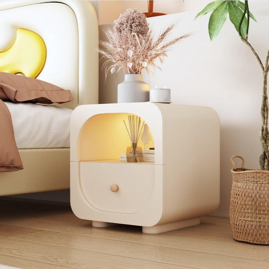 Cream nightstand with drawer beside a modern bed