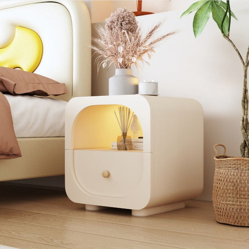 Cream nightstand with drawer beside a modern bed